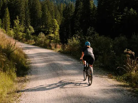 Rider climbing a gravel trail toward alpine peaks