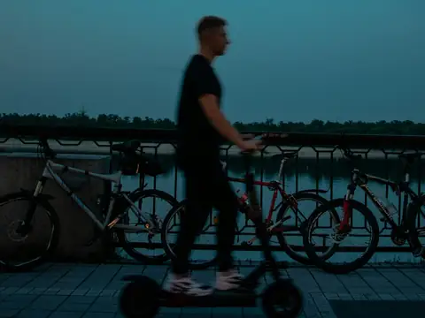 E-scooter rider on a waterfront promenade at dusk